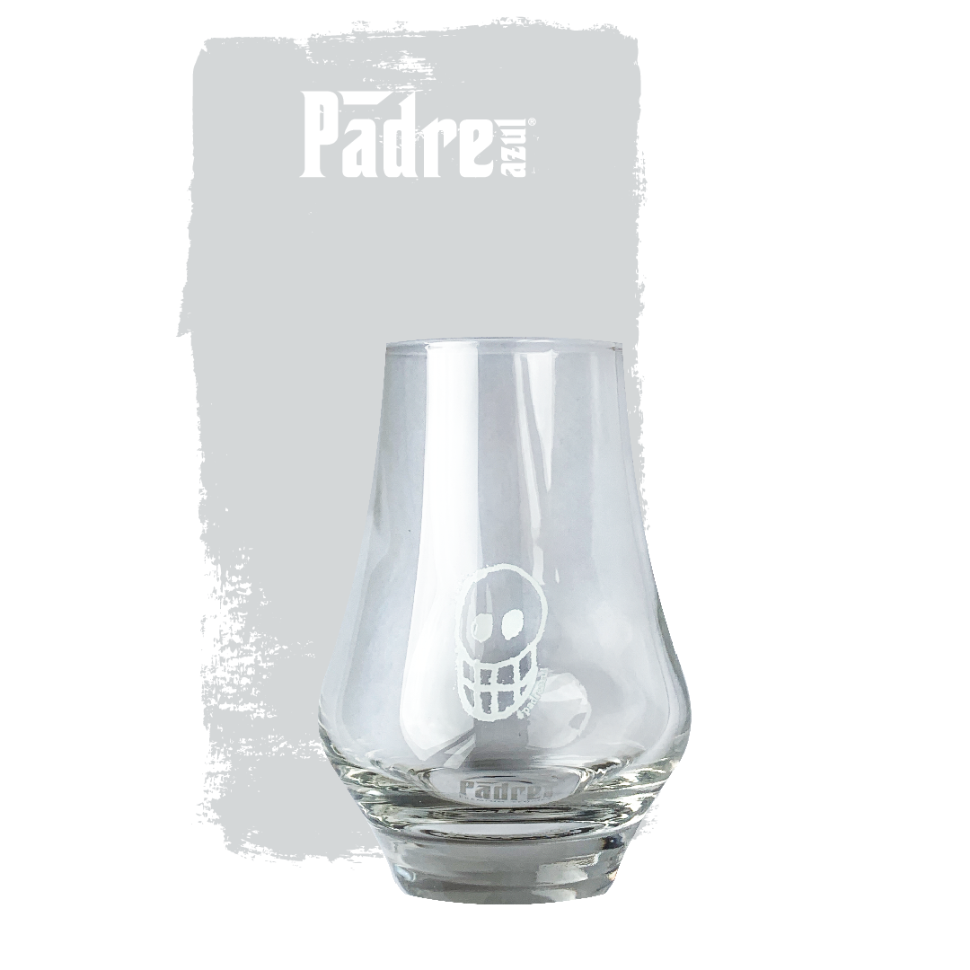 Padre Azul Signature Tasting Glass in front of a grey background. Has a solid base, gets wider towards the middle and narrows down towards the top.