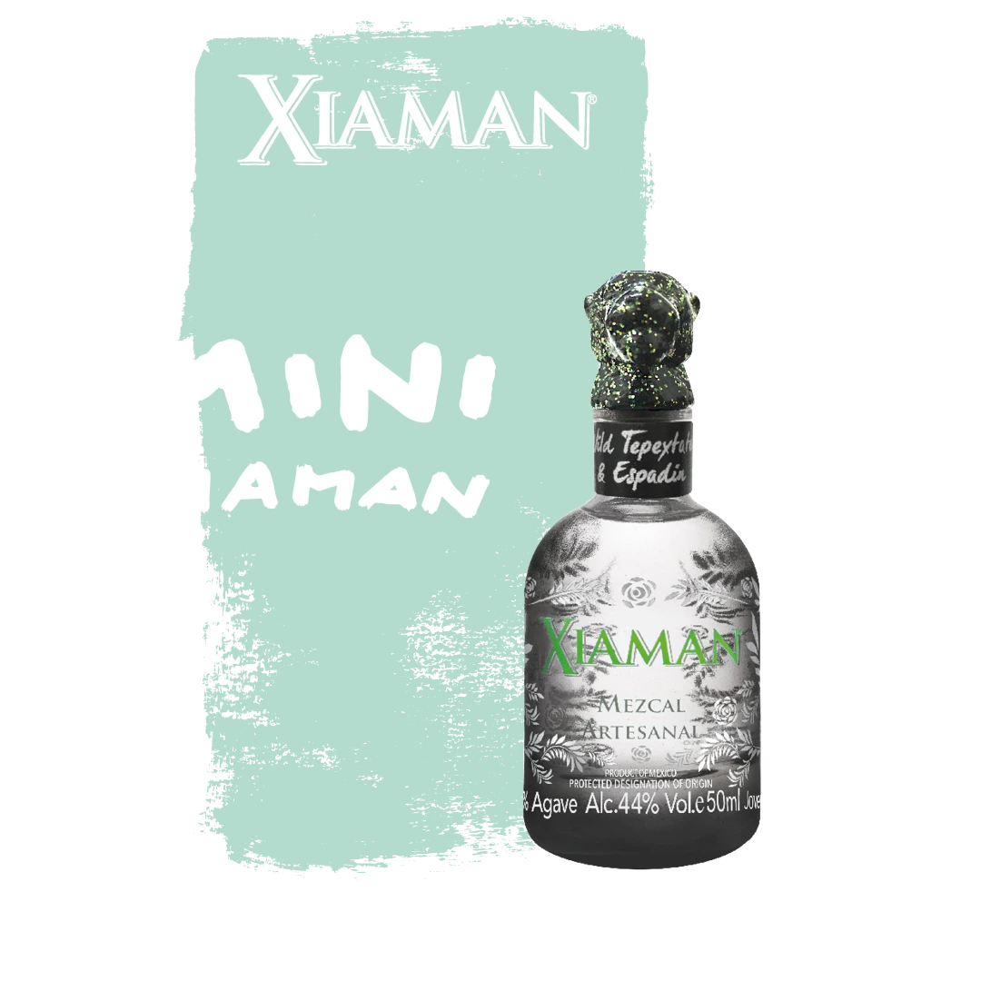 Dark grey Xiaman Mezcal 50ml bottle with green lettering and a green jaguar head bottle stopper in front of a green background.